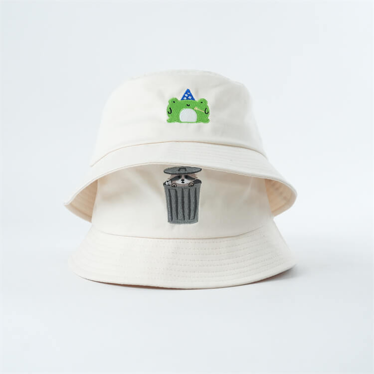 two white bucket hats with a frog and raccoon design