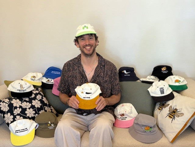 man-sitting-on-couch-surrounded-by-hats