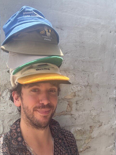 guy-with-hats-stacked-high-on-head-smiling
